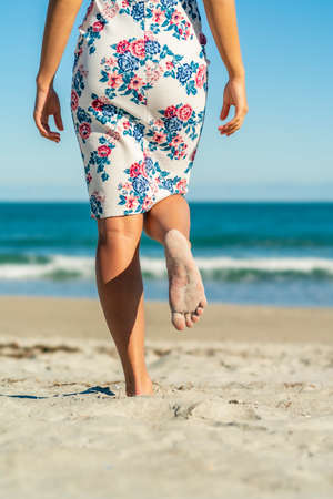 A gorgeous model walks in the sand at the beach on a beautiful dayの写真素材