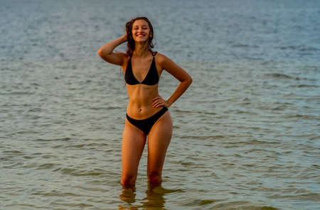 A beautiful Brunette bikini model enjoys the weather outdoors on the beachの写真素材
