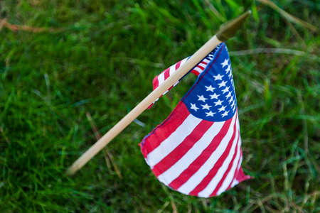 A small American flag rests in front of a fallen hero at a military cemeteryの写真素材