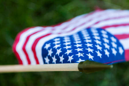 A small American flag rests in front of a fallen hero at a military cemetery