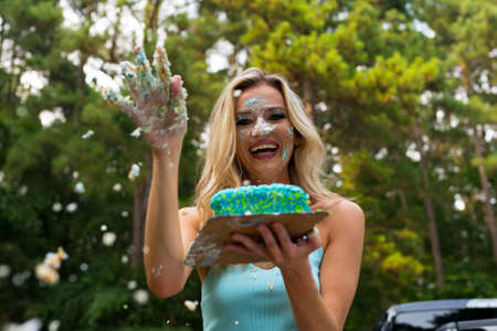 A gorgeous blonde model enjoys eating her birthday cake at a local picnic