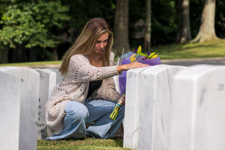 A young bride shows her grief at the burial site of a family member at a military cemeteryの写真素材