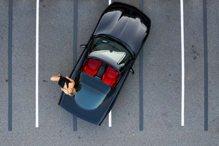 A gorgeous blonde model poses outdoors with her sports car in an urban environmentの写真素材