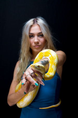 A gorgeous blonde model poses with a Boa snake in a studio environmentの写真素材