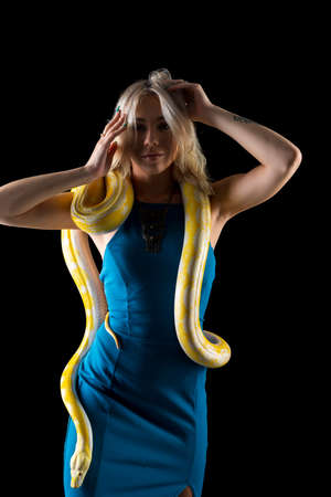 A gorgeous blonde model poses with a Boa snake in a studio environmentの写真素材
