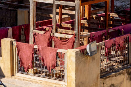 Dye reservoirs and vats in traditional tannery of city of Fez, Morocco, with men working in the dye...