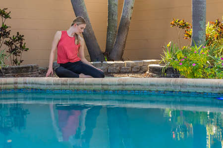 A gorgeous blonde model does yoga as she enjoys a day at the pool on a summers dayの写真素材