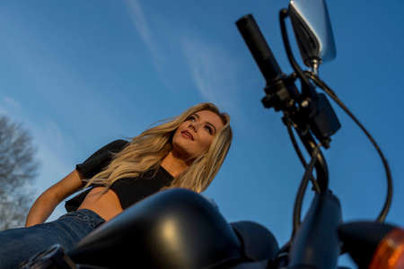 A gorgeous blonde model enjoys the outdoors while driving her motorcycle.の写真素材
