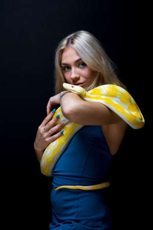 A gorgeous blonde model poses with a Boa snake in a studio environmentの写真素材