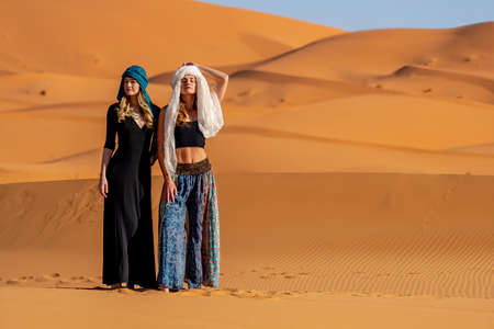 A beautiful model poses against the sand dunes in the great Sahara desert in Moroccoの写真素材