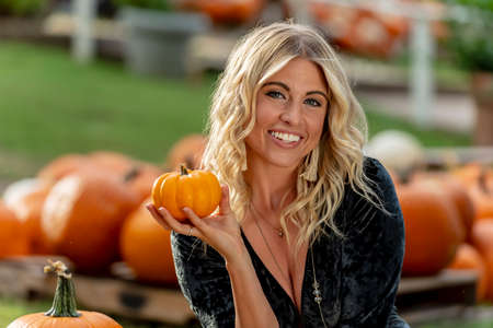 A gorgeous Blonde model poses in a pumpkin field during the halloween holidays