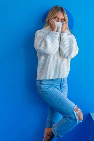 A gorgeous blonde model enjoys a day at home against a blue wall before heading to workの写真素材