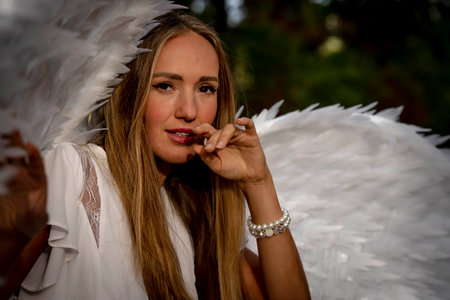 A gorgeous blonde model poses outdoors while while wearing a set of white wings for halloween.の写真素材