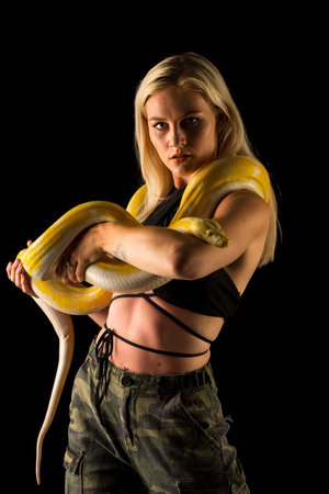 A gorgeous blonde model poses with a Boa snake in a studio environmentの写真素材