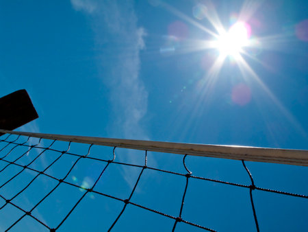 Yellow volleyball net shot from below against blue skyの写真素材