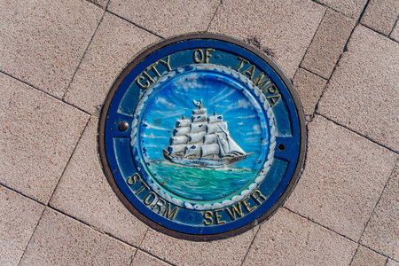 Storm sewer manhole cover on a busy street in the city of Tampa Bayのeditorial素材