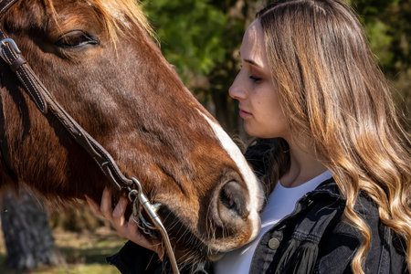 A beautiful brunette cowgirl poses with her horse before a ride in the countrysideの写真素材