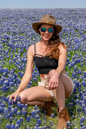 A beautiful brunette model enjoys a field of Bluebonnet flowers on a spring dayの写真素材