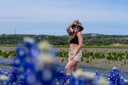 A beautiful brunette model enjoys a field of Bluebonnet flowers on a spring dayの写真素材