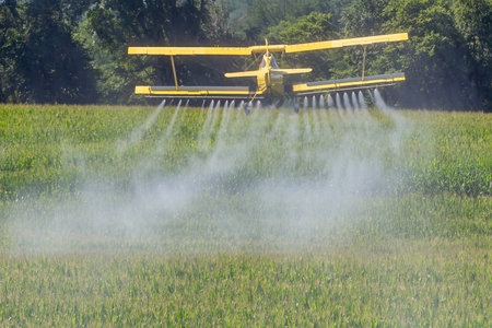 Low-flying crop duster combats pests, safeguarding fields with precision chemical spraying for...