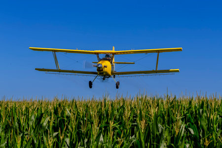 Low-flying crop duster combats pests, safeguarding fields with precision chemical spraying for insect control, ensuring healthy crop yields.のeditorial素材