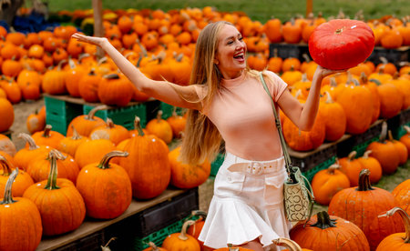 A beautiful European blonde female pics out some pumpkins and flowers for the upcoming fall festivalsの写真素材