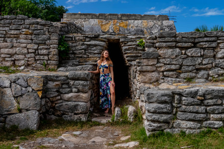 A radiant young woman explores the Xcambo Mayan ruins, her presence weaving elegance with ancient history, under the Caribbean sun's golden embraceの写真素材