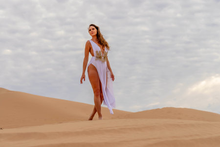 Graceful model embraces nature's beauty in the sand dunes, epitomizing elegance against the backdrop of vast, natural splendorの写真素材