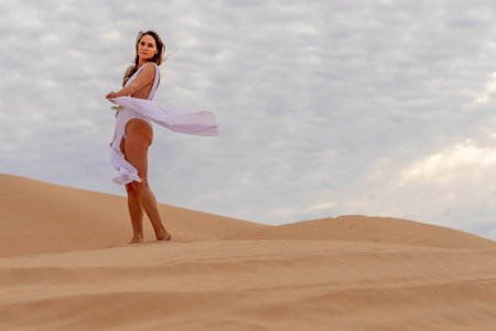 Graceful model embraces nature's beauty in the sand dunes, epitomizing elegance against the backdrop of vast, natural splendorの写真素材
