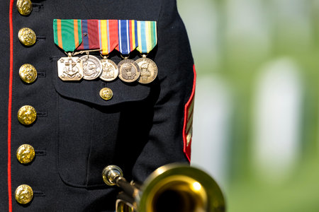 A poignant moment unfolds as a Marine plays taps, honoring a fallen veteran with a solemn salute, marking their internment at a national military cemetery.のeditorial素材