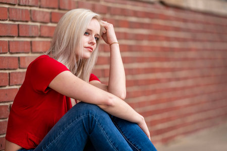 A beautiful blonde woman poses joyfully for the camera, showcasing her stylish spring clothing. With a bright smile and playful demeanor, she radiates happiness, embracing the upcoming gorgeous weather.の写真素材