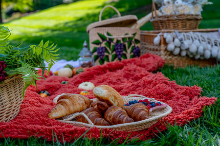 A vibrant fall picnic spread features colorful seasonal foodsâbright pumpkins, apples, charcuterie, fresh bread, cheese, and warm drinks. Surrounded by golden leaves and cozy blankets in the crisp autumn air.の写真素材