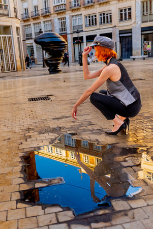 A stunning European woman strikes a confident pose on a vibrant Spanish street, accentuating her curves in a stylish outfit. The sunlit backdrop and bustling atmosphere highlight her chic, effortless elegance.の写真素材