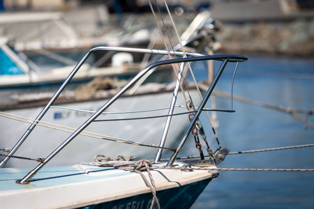 A close-up of a boat tied securely to a weathered dock, its ropes taut against sunlit wood. Reflections ripple in the water, capturing a peaceful moment by the marina's edge.の写真素材