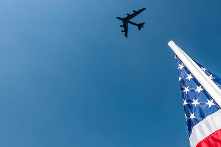 A B-52 soars above the stadium, trailing white contrails across a clear blue sky. Below, an American...