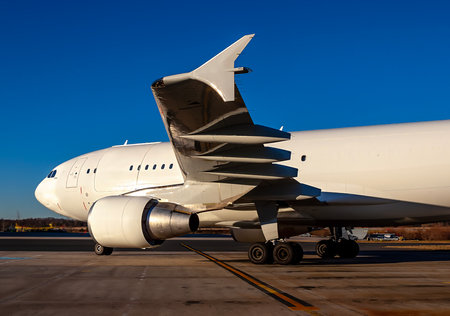 A commercial cargo aircraft rests on the tarmac of a bustling international airport, its massive...