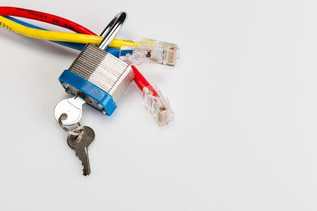 An Ethernet cable coiled with a metal padlock around its connector lies on a white background, symbolizing cyber security, data protection, and the safeguarding of digital networks.の写真素材