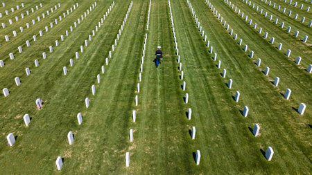 A poignant moment unfolds as a Marine plays taps, honoring a fallen veteran with a solemn salute, marking their internment at a national military cemetery.の写真素材