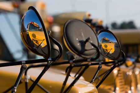 Bright yellow school buses line up in the morning light, engines humming, doors open, and drivers...