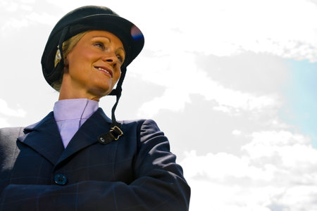 A young equestrian gracefully prepares for a horse show, adjusting her riding gear with poise and...
