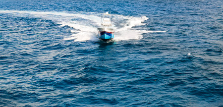 A sleek motorboat speeds across the ocean, cutting through waves with power. White spray and a foamy...