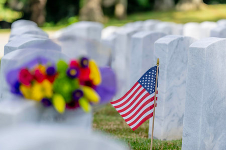 Rows of marble military headstones stand in precise alignment, adorned with flowers and American flags. The serene field reflects profound respect and dignity for the fallen heroes who served our country.の写真素材
