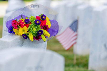 Rows of marble military headstones stand in precise alignment, adorned with flowers and American flags. The serene field reflects profound respect and dignity for the fallen heroes who served our country.の写真素材