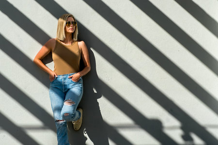 A beautiful blonde woman basks in the warm summer sun, her golden hair glowing as she smiles, savoring the gentle breeze and the vibrant beauty of the day.の写真素材