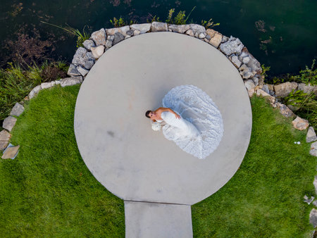 A radiant bride stands elegantly in her exquisite wedding dress, intricate lace cascading delicately, shimmering in soft light, her joyful eyes reflecting excitement for the love-filled journey ahead.の写真素材