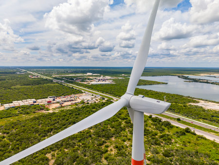 An aerial view of a wind turbine shows its massive blades spinning gracefully over open fields, harnessing wind energy to generate clean, renewable power and reduce dependence on fossil fuels.の写真素材
