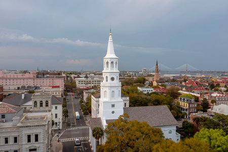 A stunning aerial view of Charleston, South Carolina reveals colorful historic homes, cobblestone streets, and waterfront charm framed by lush trees and shimmering coastal light.