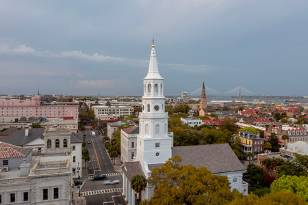 A stunning aerial view of Charleston, South Carolina reveals colorful historic homes, cobblestone streets, and waterfront charm framed by lush trees and shimmering coastal light.
