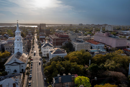 A stunning aerial view of Charleston, South Carolina reveals colorful historic homes, cobblestone streets, and waterfront charm framed by lush trees and shimmering coastal light.の写真素材