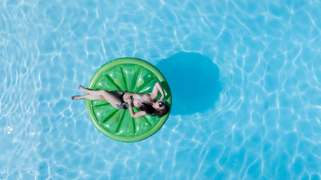 A Brunette bikini model relaxes by a Caribbean pool, soaking up the sun and gentle Tradewinds. She...